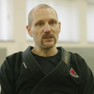 Kampfkunstmeister in einem schwarzen Kampfsport-Anzug.