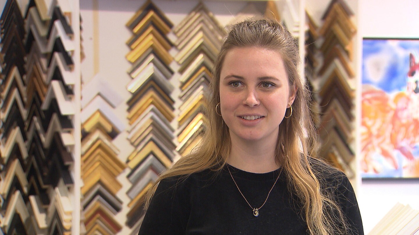 Junge, blonde Frau vor goldenen Bilderrahmen