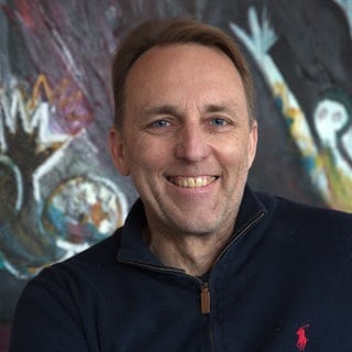 Marc vom Ende, Parfümeur, lächelt vor einem bunten Hintergrund in die Kamera. Würzig-holzig, Chypre-grün: Den Duft eines Parfums zu umschreiben ist schon schwer. Noch schwerer: ein Parfum zu kreiieren. In SWR1 Leute ein Meister seines Fachs: Marc vom Ende. Er erzählt, wie die großen Düfte wie etwa Chanel, Guerlain oder Herrera entstanden sind und wie schwer es ist, ein Parfüm zu kreiren