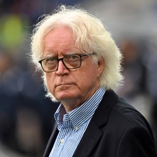 Der ehemalige Fußballtrainer Winnie-Schäfer drehet seinen Kopf und schaut in die Kamera.  Er ist 75 Jahre und kein bisschen Fußball müde: KSC Legende Winfried Schäfer will es immer noch wissen. Findet das, was der VfB unter Hoeneß macht, "unheimlich gut" und will jetzt die Fußball-Nationalmannschaft von Ghana in die WM 2026 führen.