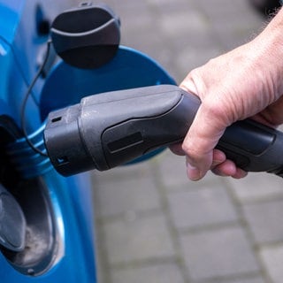 Ein Ladekabel wird in ein E-Auto gesteckt.