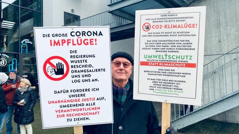Mann aus Bad Wörishofen in Bayern, der mit seinen selbstgestalteten Schildern an der Querdenker Demonstration in Karlsruhe teilgenommen hat (Foto: SWR, Foto: Johannes Stier ) Mann aus Bad Wörishofen in Bayern, der mit seinen selbstgestalteten Schildern an der Querdenker Demonstration in Karlsruhe teilgenommen hat