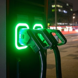 An einer Schnellladesäule für E-Autos leuchten Ladekabel grün.