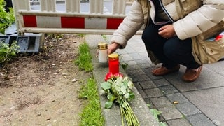 Menschen legen am Tag nach dem Unfall Blumen am Unfallort am Olgaeck ab oder stellen Kerzen auf.