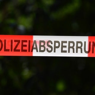 Ein Absperrband der Polizei sichert einen Tatort. In einem Wald bei Sindelfingen haben Arbeiter eine Frauenleiche entdeckt.
