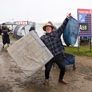 Ein Festivalbesucher steht bei "Rock am Ring" nach starkem Regen im Matsch.