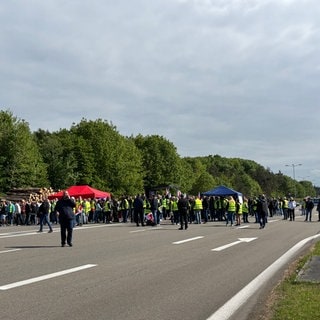 Viele Menschen stehen in einer Gruppe auf einer Straße - Protest der Zivilbeschäftigen an der Air Base Ramstein 