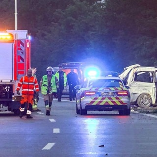 Polizei- und Feuerwehrwagen stehen auf der Autobahn 48 nahe Koblenz an einer Unfallstelle. Dort ist ein Kleinlaster von der Straße abgekommen und drei Menschen starben.