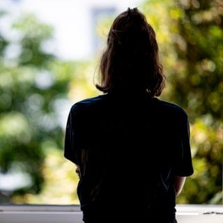 Eine Frau steht in ihrer Wohnung an einem Fenster (gestellte Szene). Symbolbild für Betroffener erzählt, wie er mit Depression lebt.