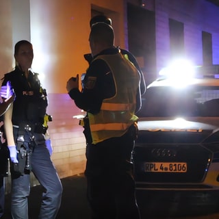 Einsatzkräfte stehen im Dunkeln vor einem Haus in Mainz-Mombach, wo ein Streit eskalierte.
