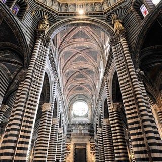 Das Mittelschiff des Domes mit seinen Schwarz-weiss gestreiften Marmorsäulen, Kreuz- und Rundbögen, Siena, Toskana, Italien, Europa. Archivfoto.