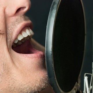 Symbolbild "Themenwoche. Das Instrument des Jahres: Die Stimme": Ein Mann singt in ein Mikrofon