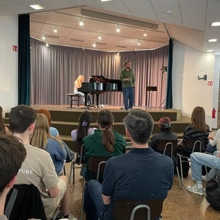 Julian Prégardien und die Pianistin Anna Gebhard am Schwetzinger Hebelgymnasium auf Bühne vor Schülern der 11. Klasse