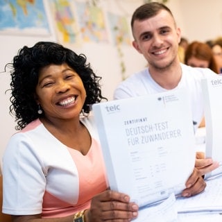 Angela Nwaubani aus Nigeria und Enver Latifi aus dem Kosovo freuen sich über ihre Zertifikate "Deutsch-Test für Zuwanderer", die sie für die erfolgreiche Teilnahme an einem Integrationskurs für Zuwanderer des Bundesamtes für Migration (BAMF) bekommen haben. Die deutsche Sprache gilt in Deutschland als Schlüssel zu einer erfolgreichen Integration. Deshalb hat die Bundesregierung 2005 die staatlich geförderten Integrationskurse eingeführt. 