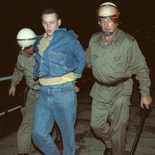 Zwei Polizisten führen einen Mann ab: Zu schweren Ãbergriffen von Rechtsradikalen auf Ausländerheime in Hoyerswerda und weiteren Orten Sachsens und anderen ostdeutschen Bundesländern kam es in den Tagen um den 22.9.1991. In Hoyerswerda, wo Rechtsextremisten die Polizei angriffen und sich mit Gegendemonstranten prügelten, wurden zahlreiche Personen festgenommen. 