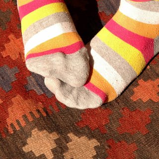 Füße in wärmenden Ringelsocken: Neigen Frauen eher zu kalten Füßen als Männer?