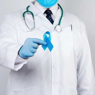 Ein Arzt hält sinnbildlich für Prostatakrebsvorsorge eine blaue Schleife in die Kamera - das Symbol für das Prostatakarzinom. Nun wurde eine neue Leitlinie zur Vorsorge und Behandlung veröggentlicht.